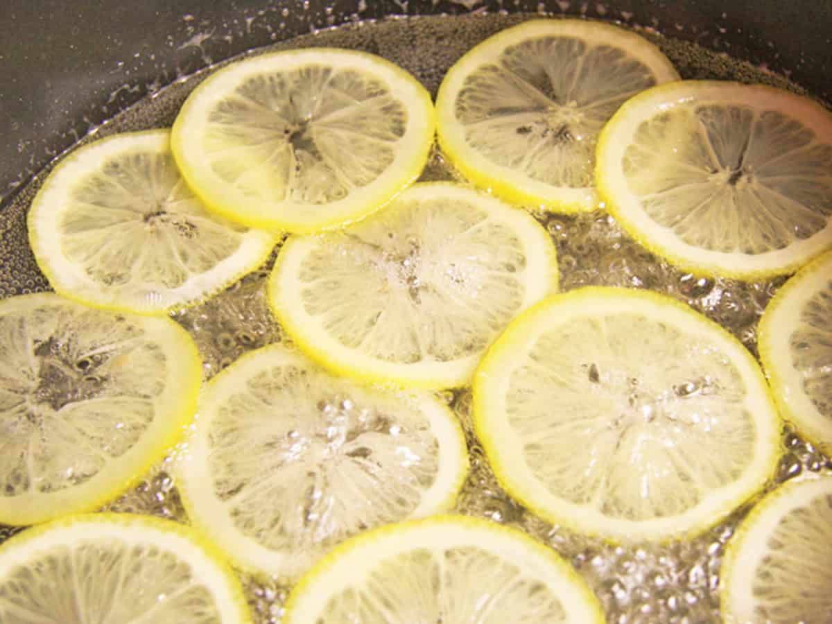 Lemon slices boiling in syrup for candied lemon recipe.