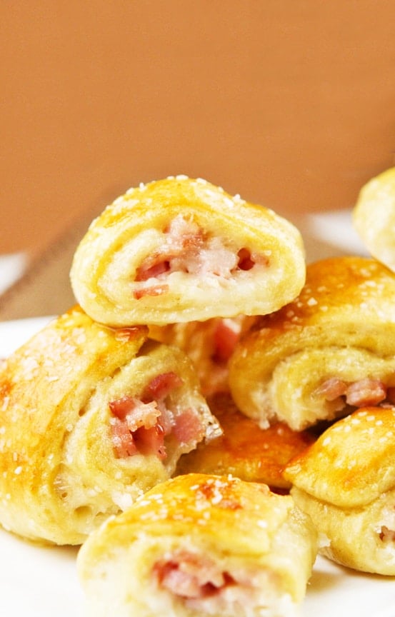 Pretzel bites filled with ham and cheese stacked one on top of the other. 