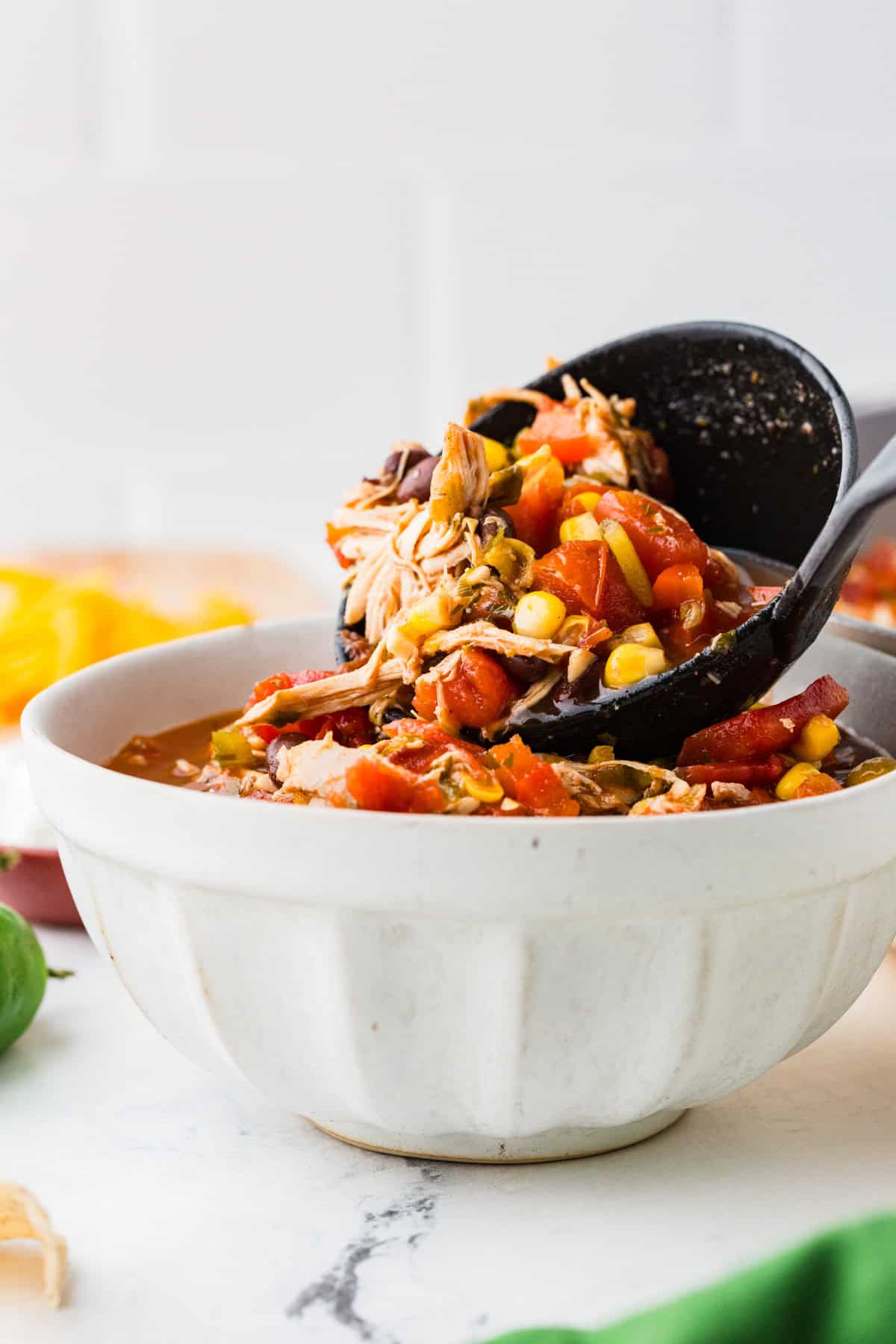 Ladle pouring taco soup into a serving bowl.