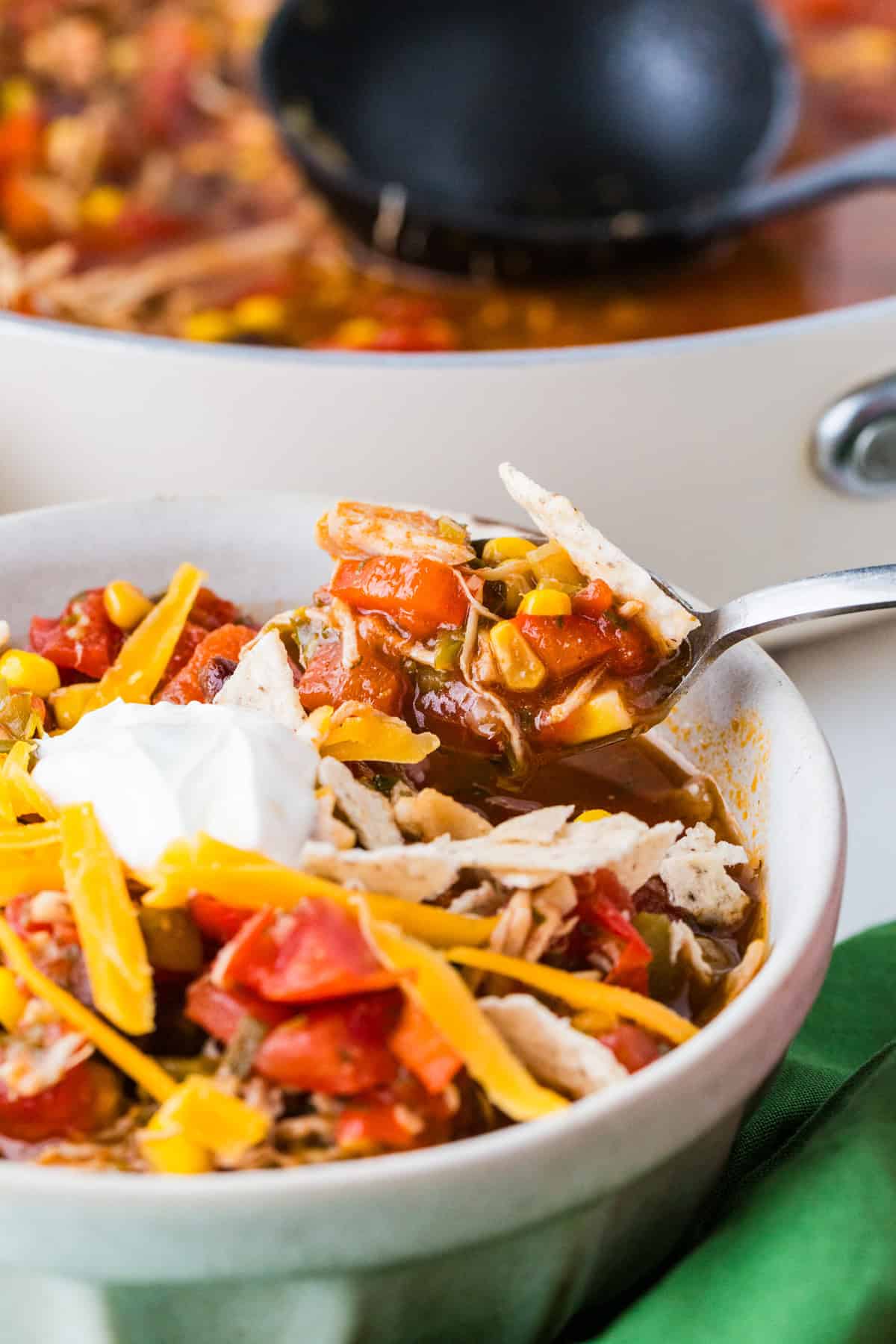 Spoon pulling out a bite of taco soup from a bowl.