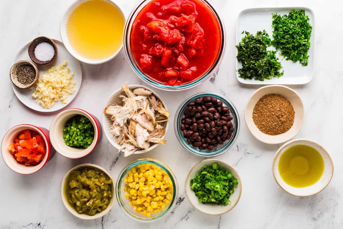 Taco soup ingredients in individual bowls, lined up on a counter.