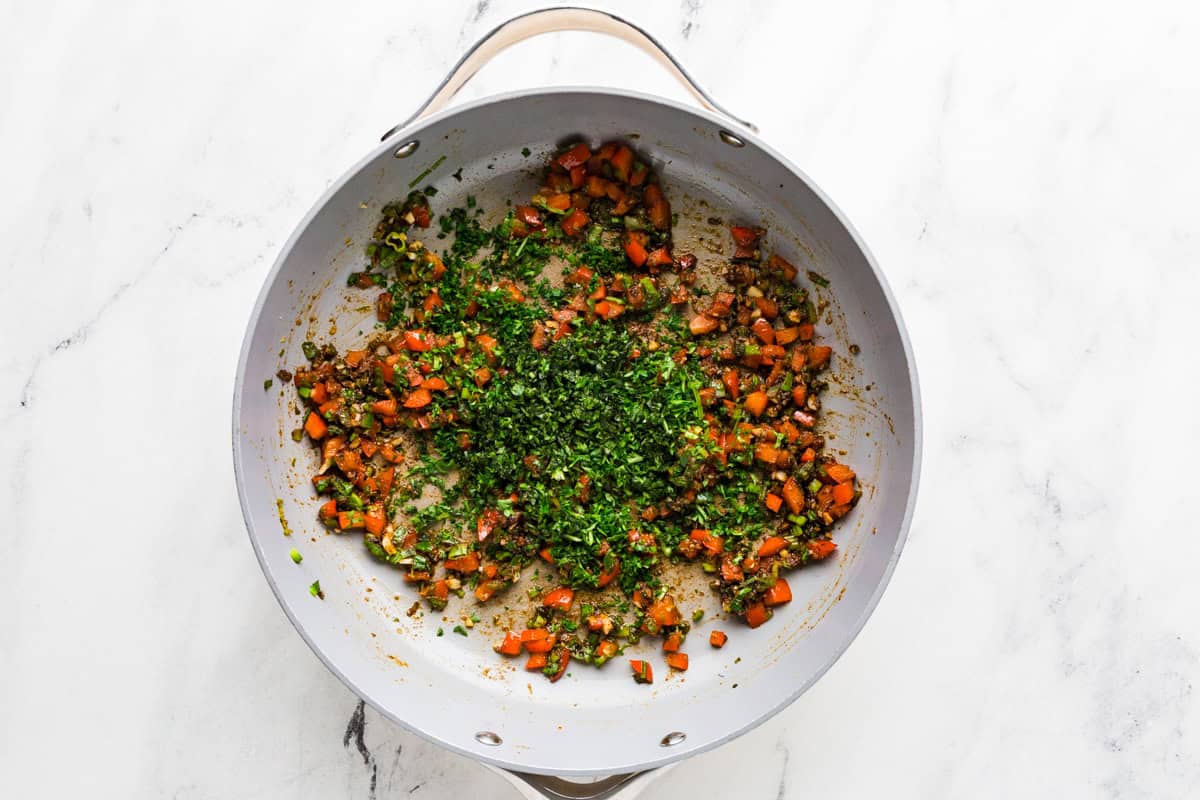 Tomatoes and herbs cooking in a pan.