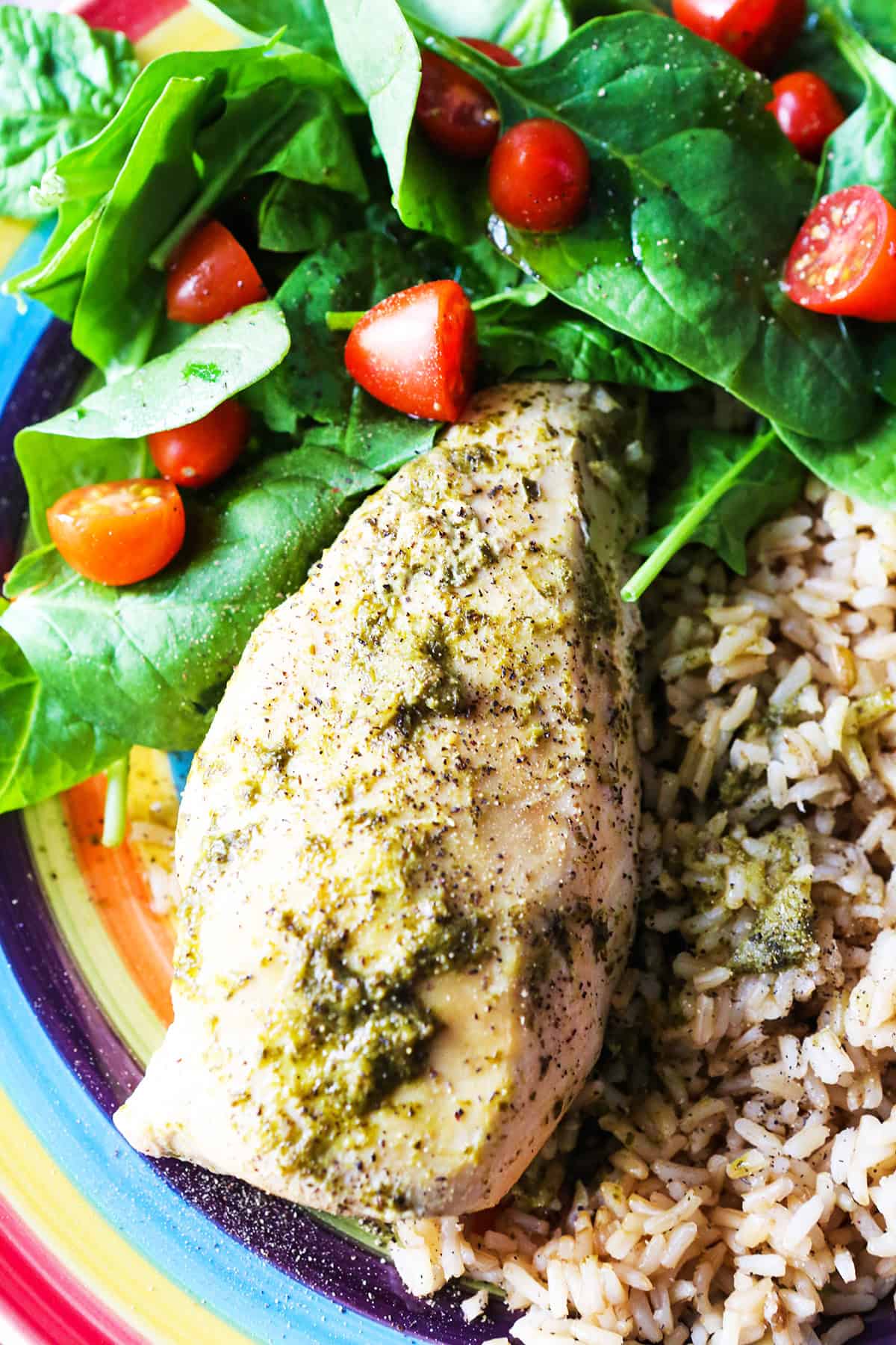 Plate of pesto chicken, rice and a spinach salad.