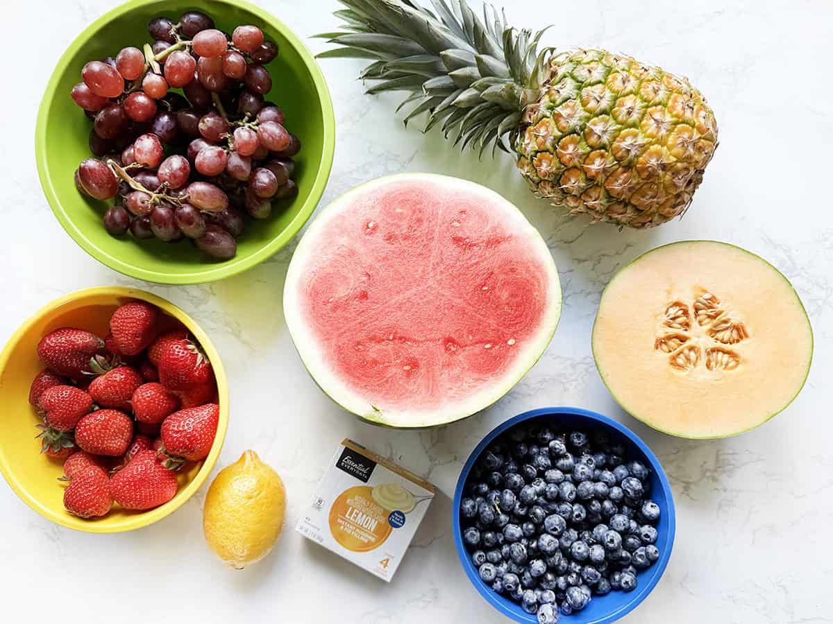 Fruits for fruit salad on a white counter.