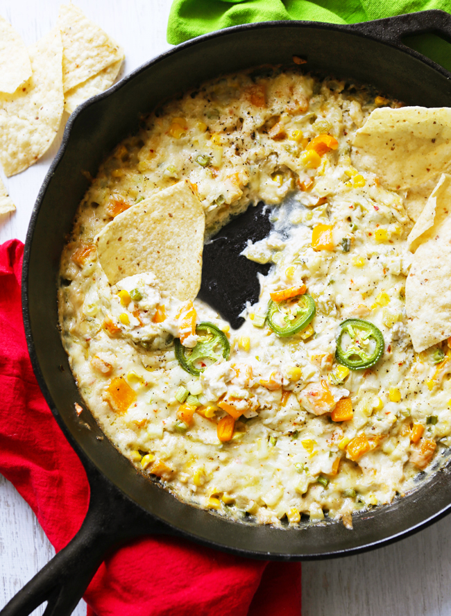 Cast iron skillet filled with crab dip and a chip tucked into the skillet. 