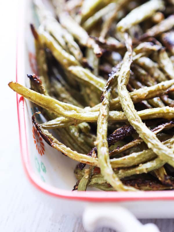 Oven roasted green beans topped with parmesan cheese in a baking dish. 