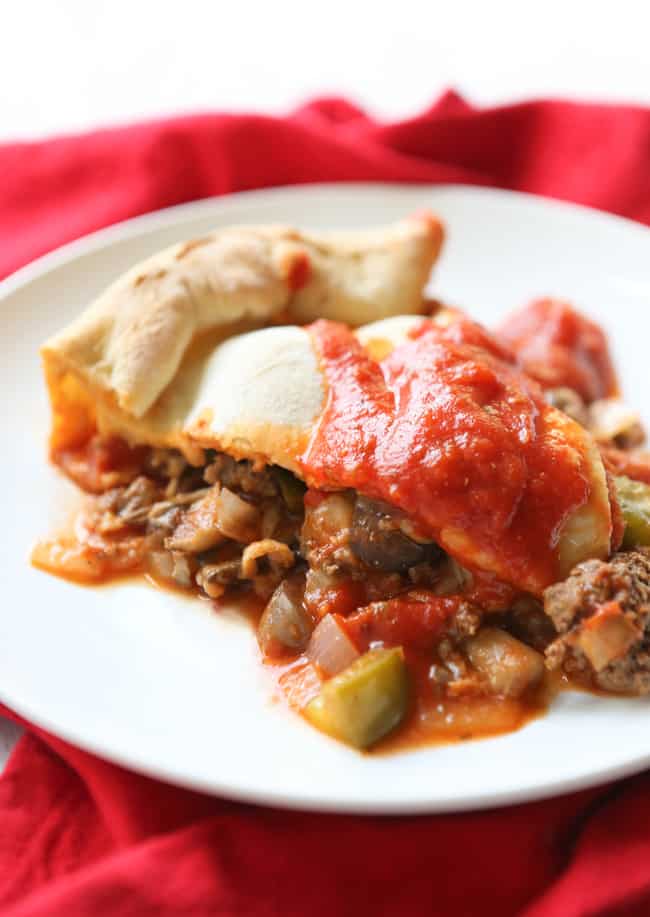 Slice of meaty calzone with a drizzle of pizza sauce over the top.