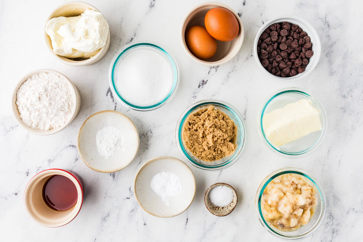 Ingredients for chocolate chip banana bread in bowls on a white counter.