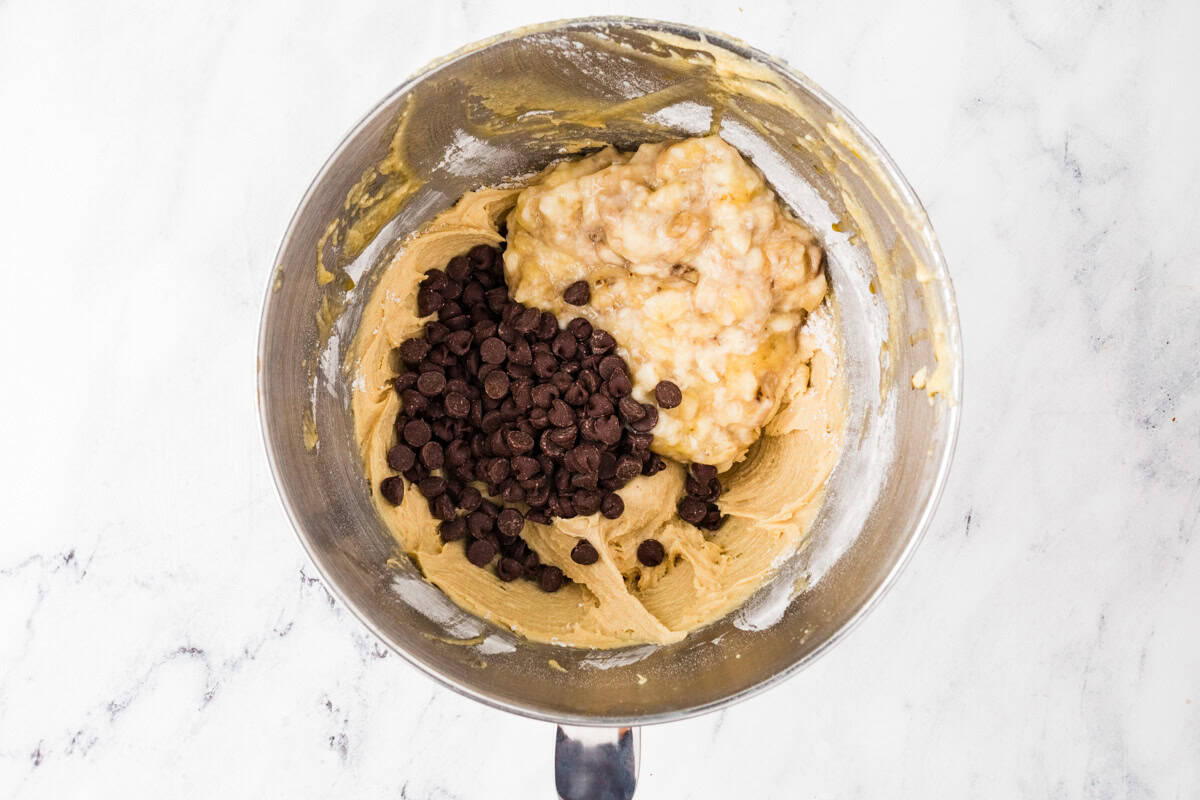 Mixing bowl with batter, chocolate chips and mashed banana.