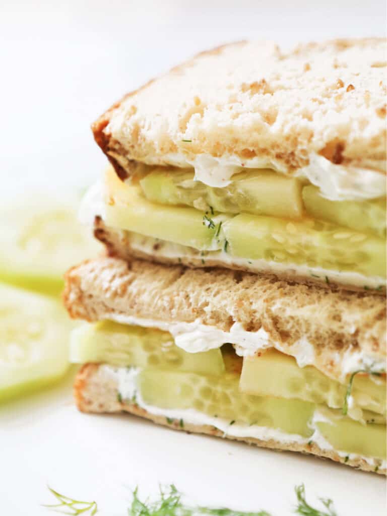 Two halves of a cucumber cream cheese sandwich. 