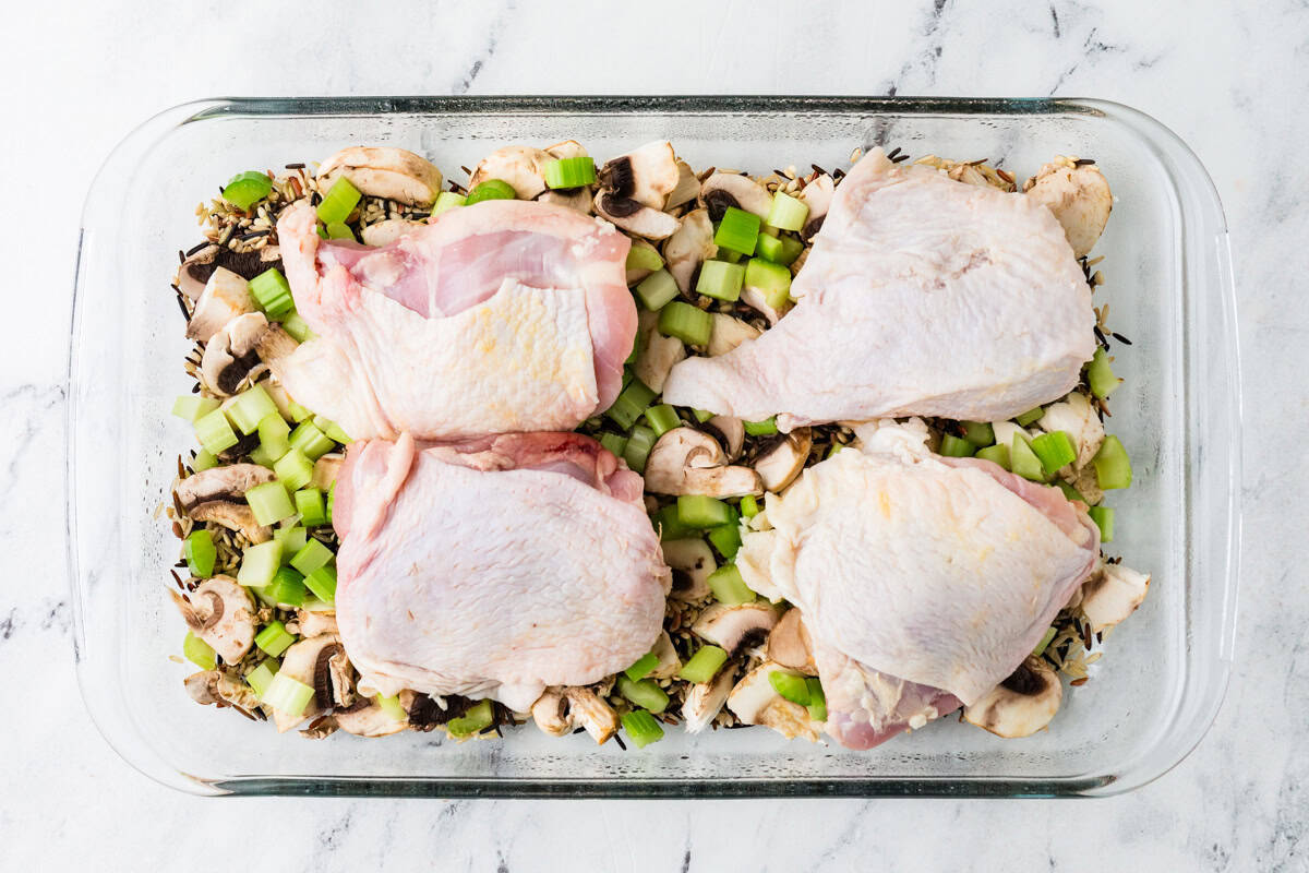 Chicken thighs on top of chopped veggies and rice.