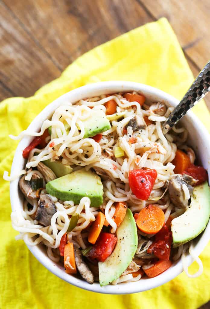 Spoon tucked into a full bowl of ramen and veggies. 