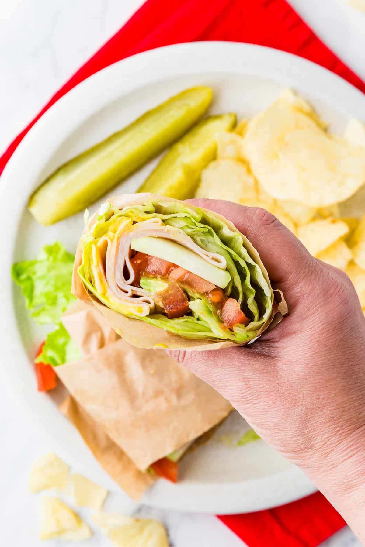 Hand holding a Jimmy Johns unwich, revealing insides filled with meat and veggies.