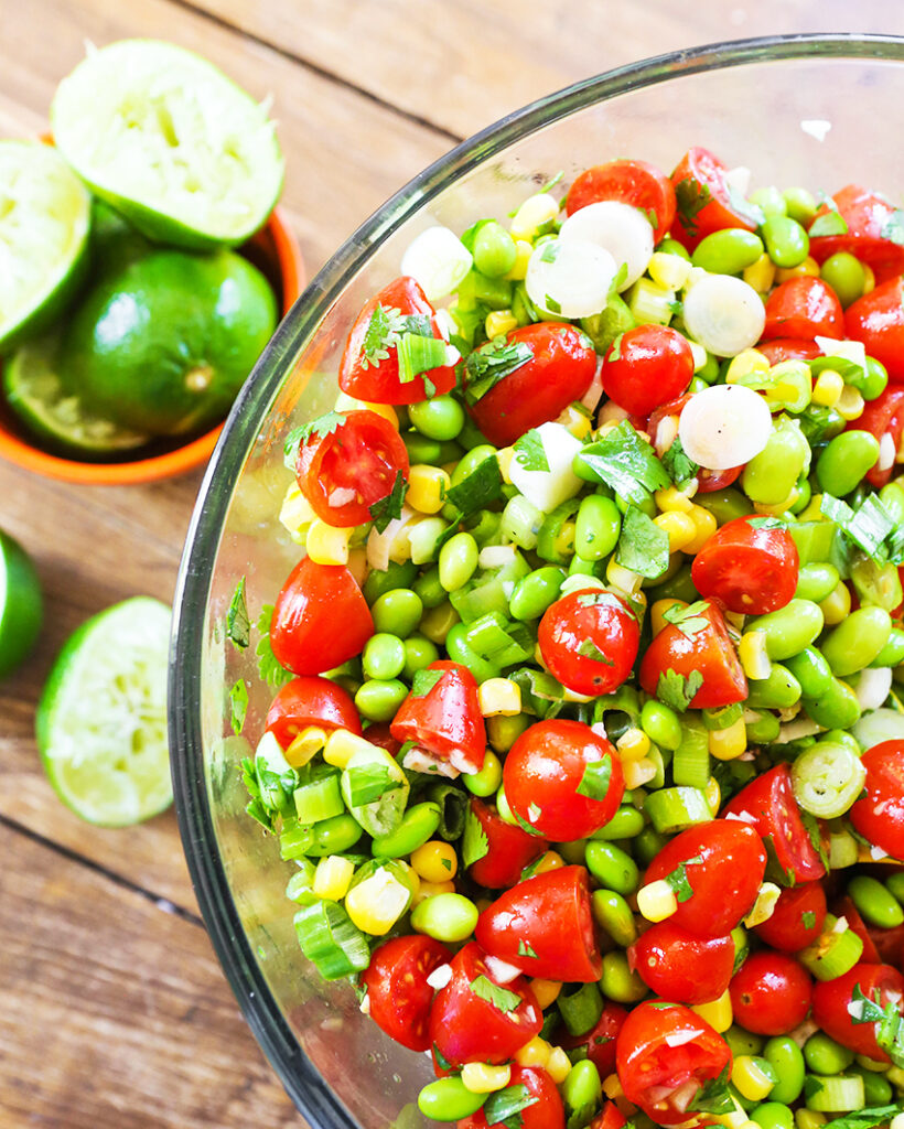 Serving bowl filled with fresh edamame, cherry tomatoes and corn.