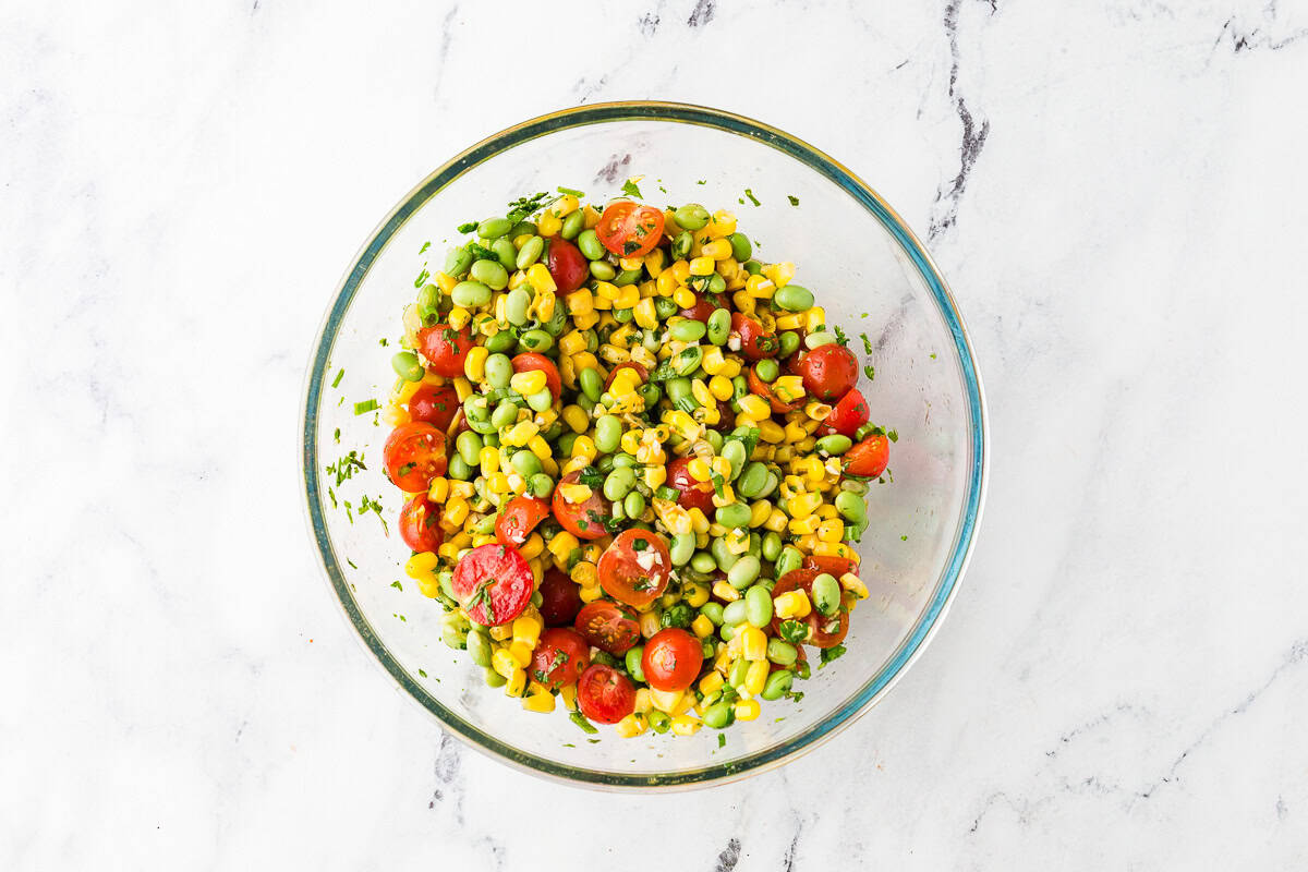 All ingredients for tomato summer salad in a glass bowl.