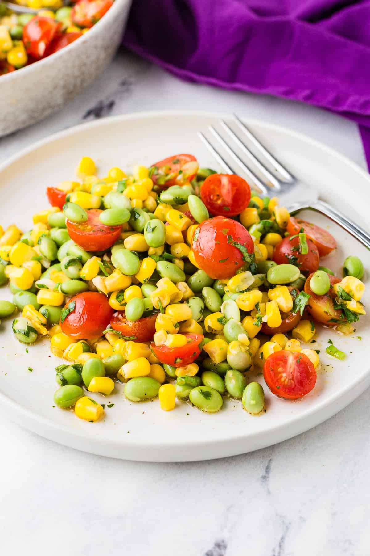 Serving of edamame summer salad on a plate with a fork ready to dig in.