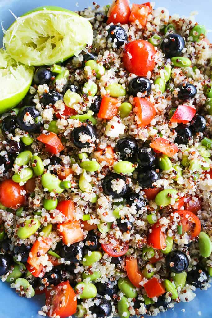 Two halves of a lime with the juice squeezed out sitting on quinoa edamame salad. 