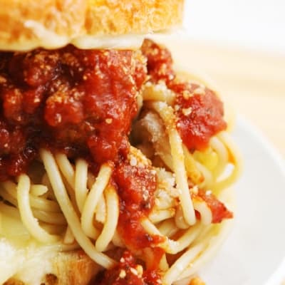 A close up shot of the side of spaghetti and meatballs grilled cheese sandwich. 