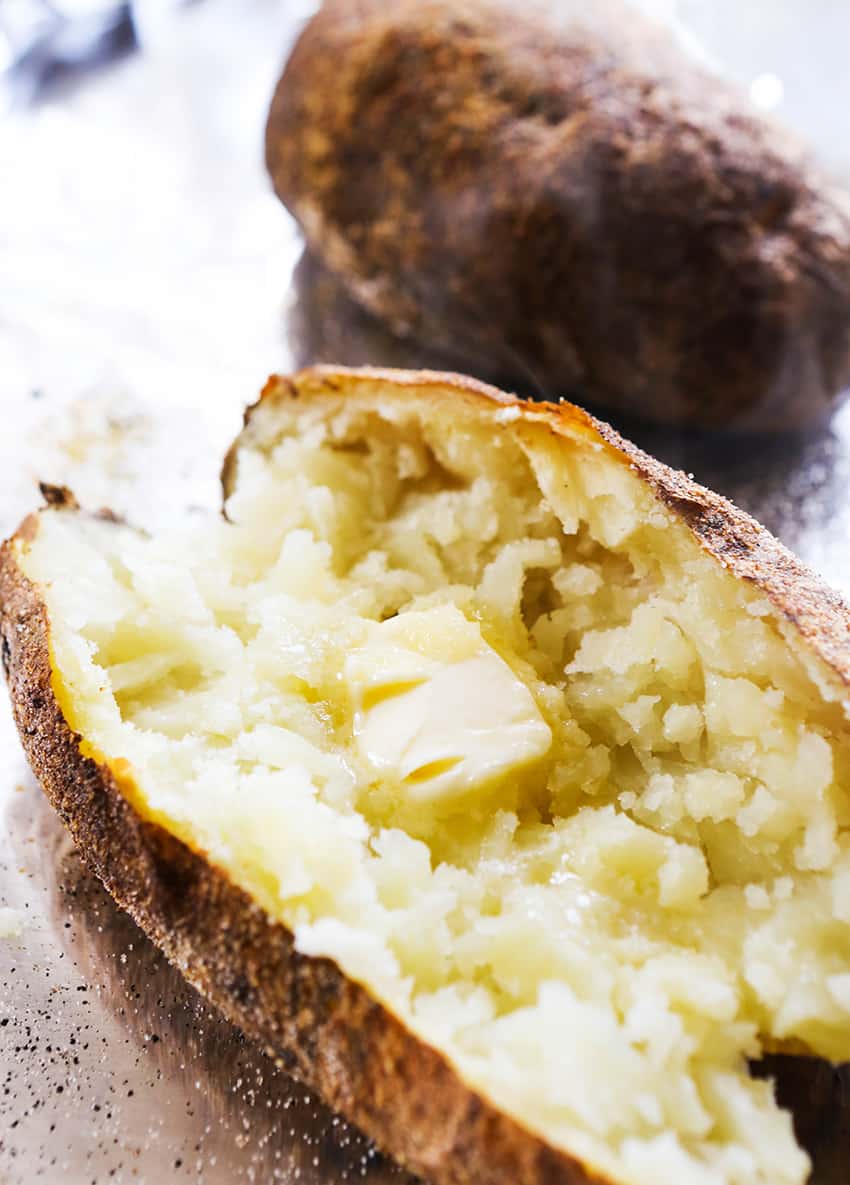 Center of a perfectly cooked baked potato exposed, with a melting pat of butter inside.