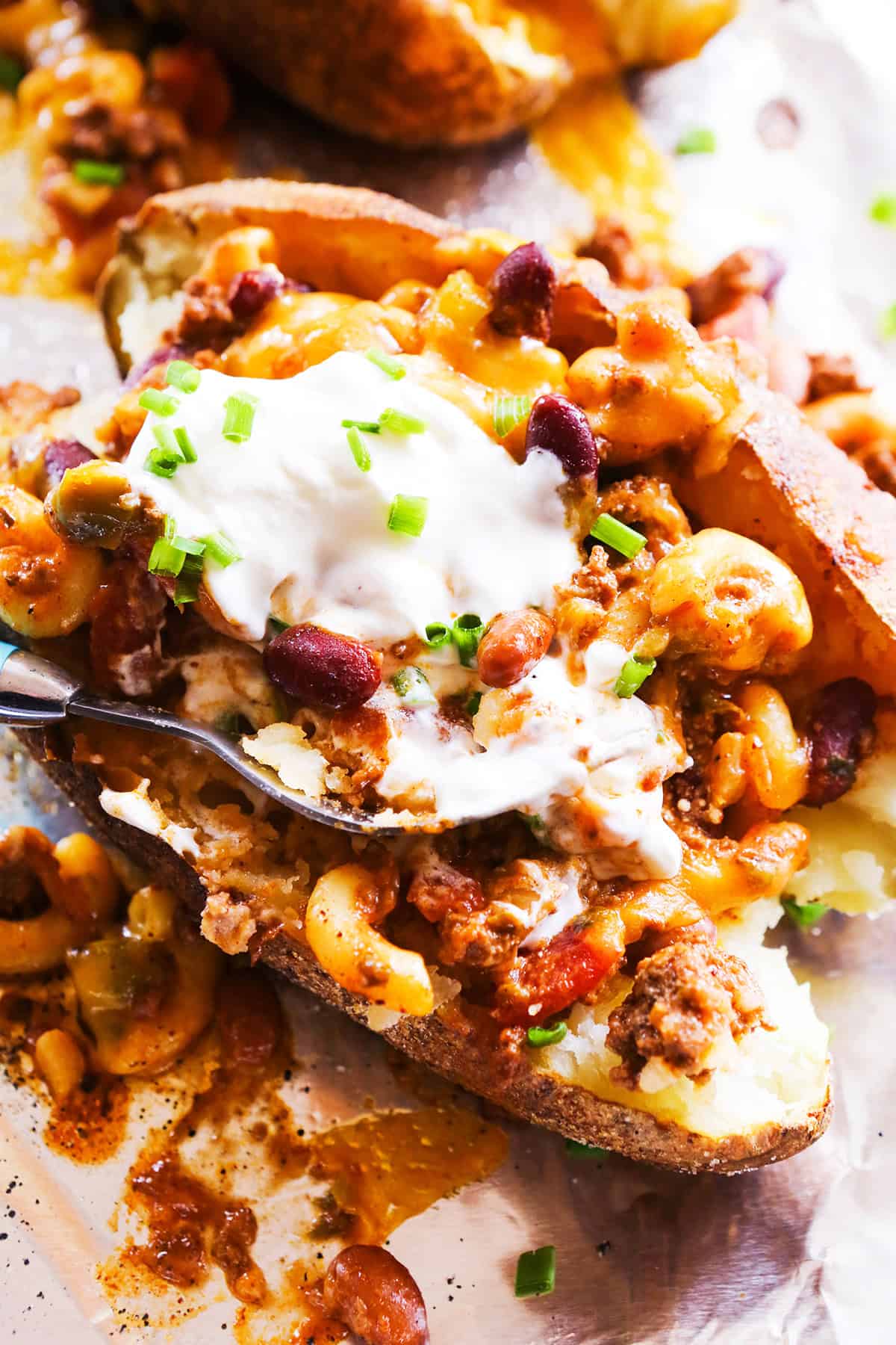 Fork digging into a baked potato fully loaded.