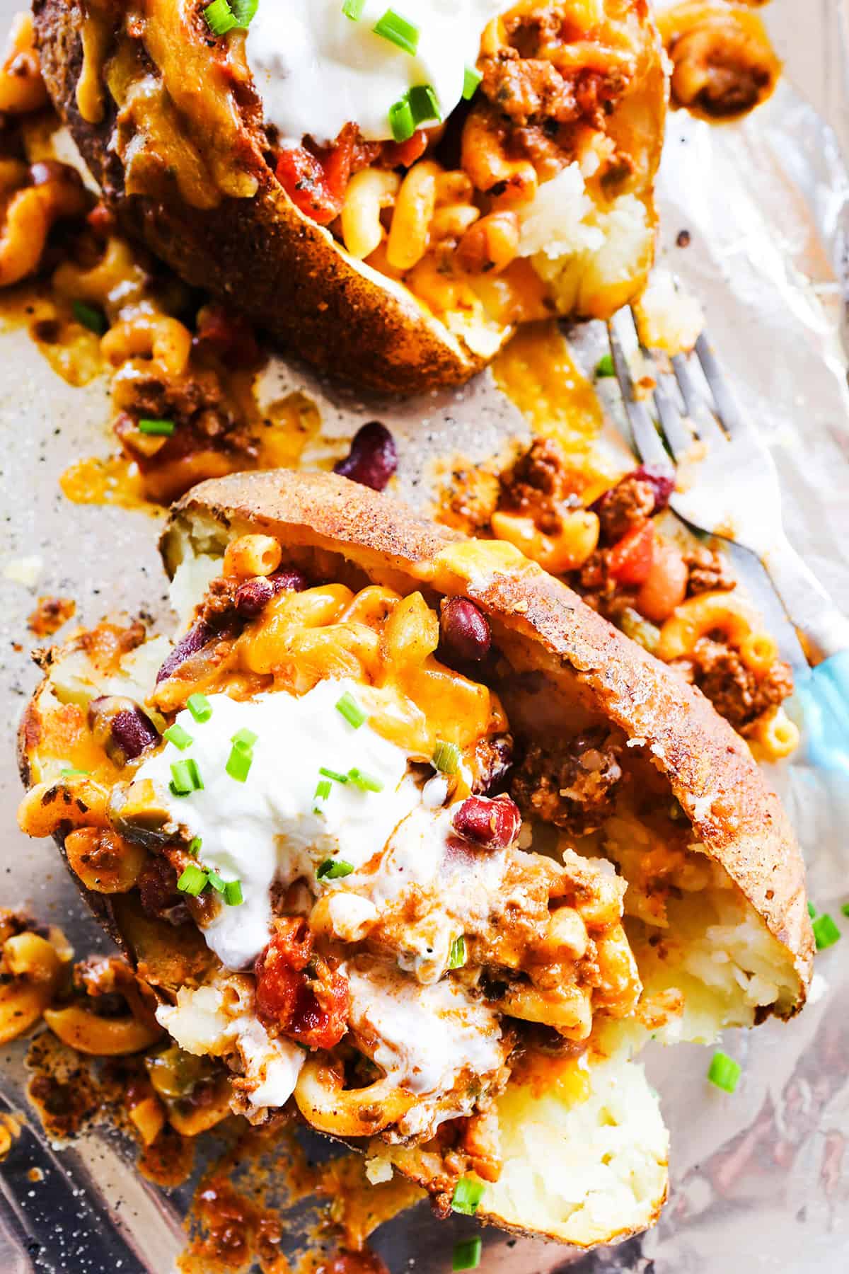Top view of two baked potatoes loaded with chili and other toppings.