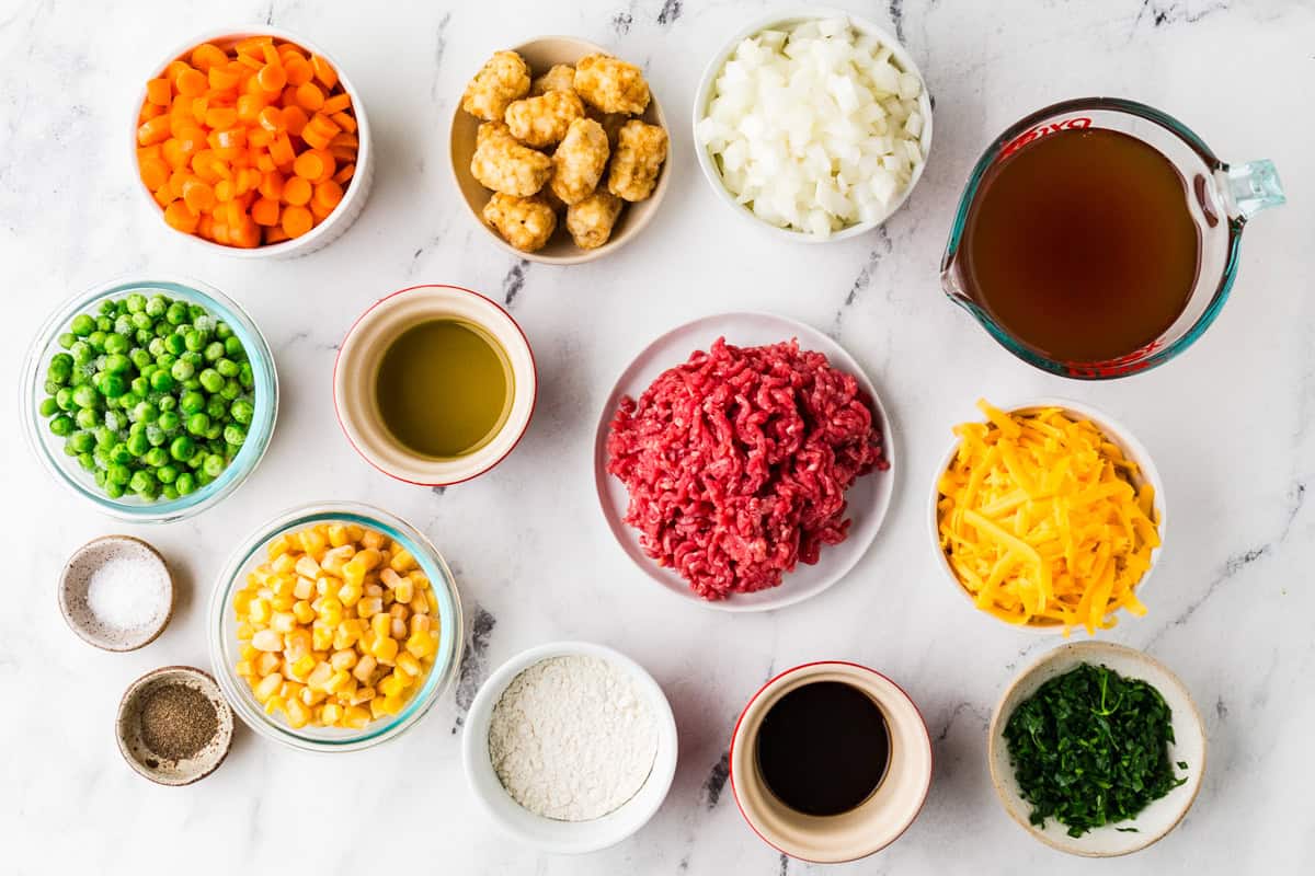 Ingredients for tater tot shepherds pie in individual bowls on a white counter.