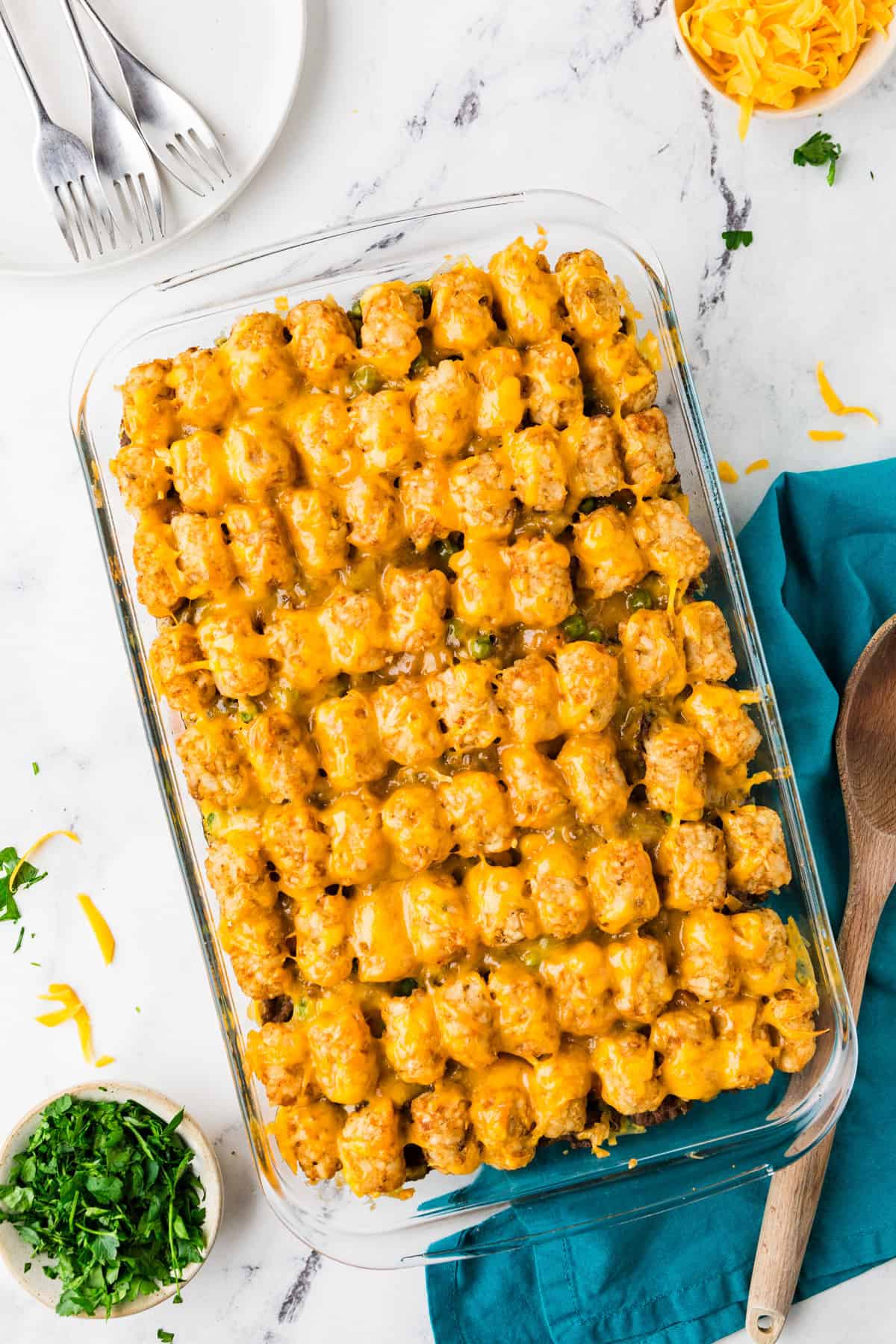 Top view of a full pan of a cheesy tater tot casserole in a glass baking dish.