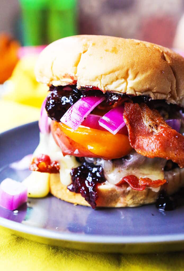 Burger topped with peaches, red onions, jam and bacon.