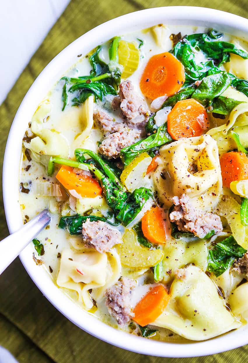 Top view of a bowl filled with tortellini soup with carrots and sausage.