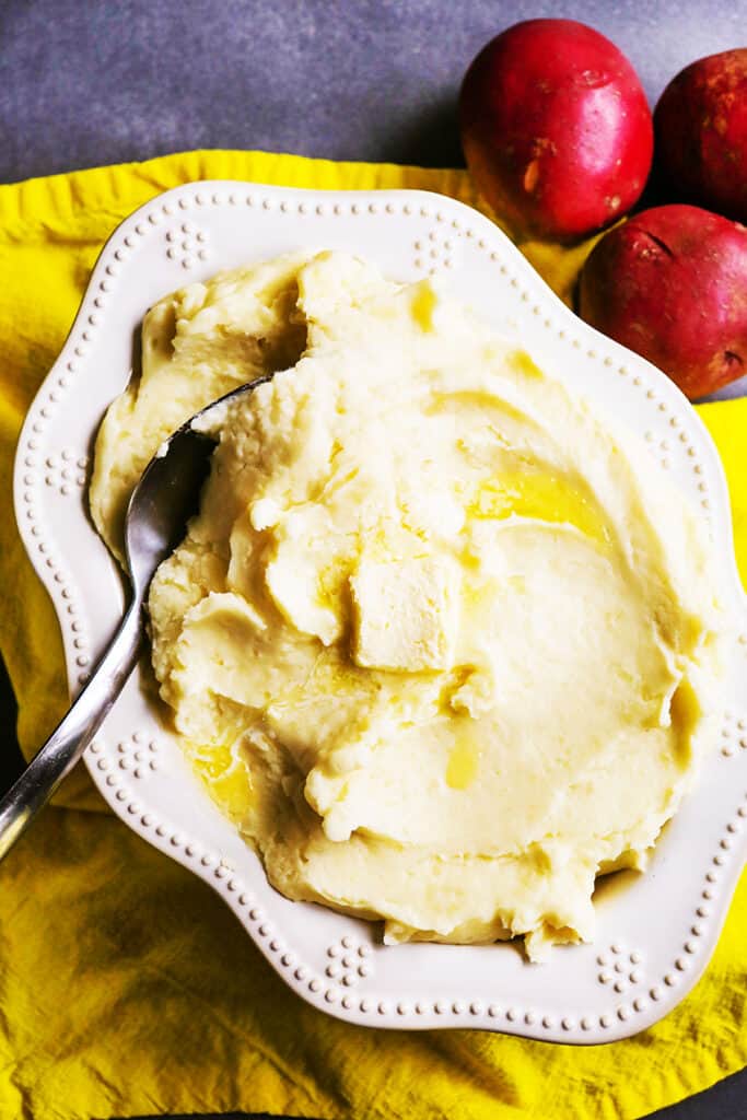 Top view of a bowl filled with mashed potatoes and a serving spoon tucked into it. 