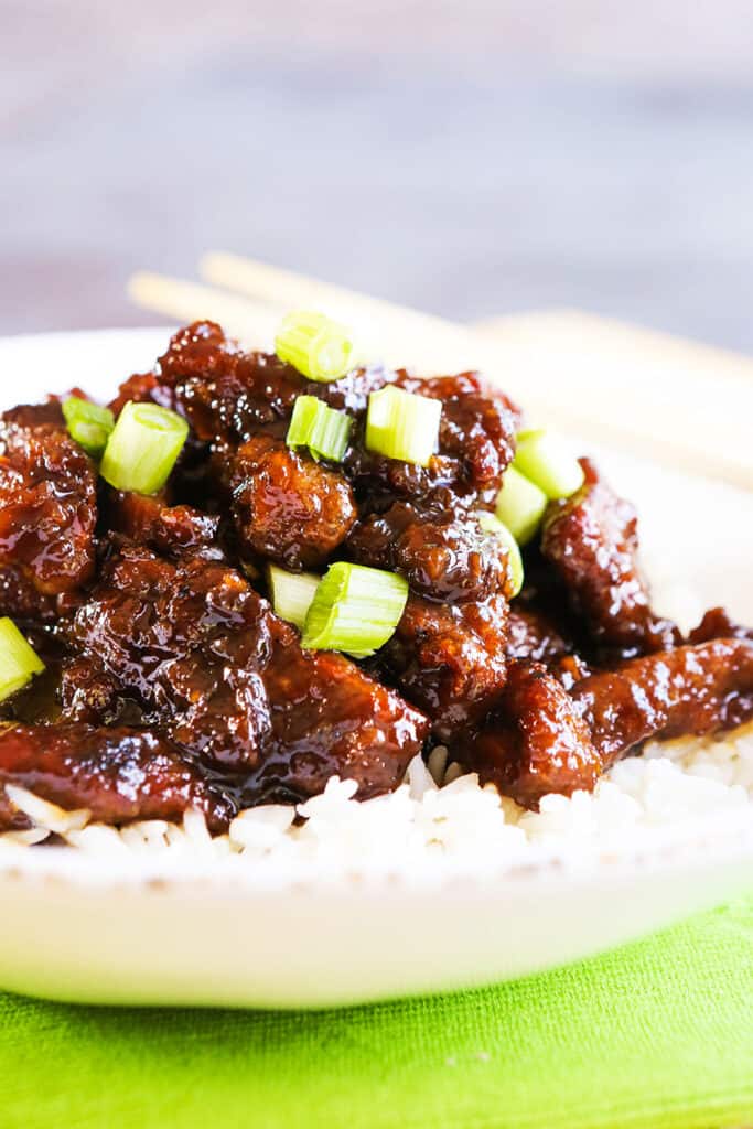 Mongolian beef garnished with green onions laid over a bed of white rice. 