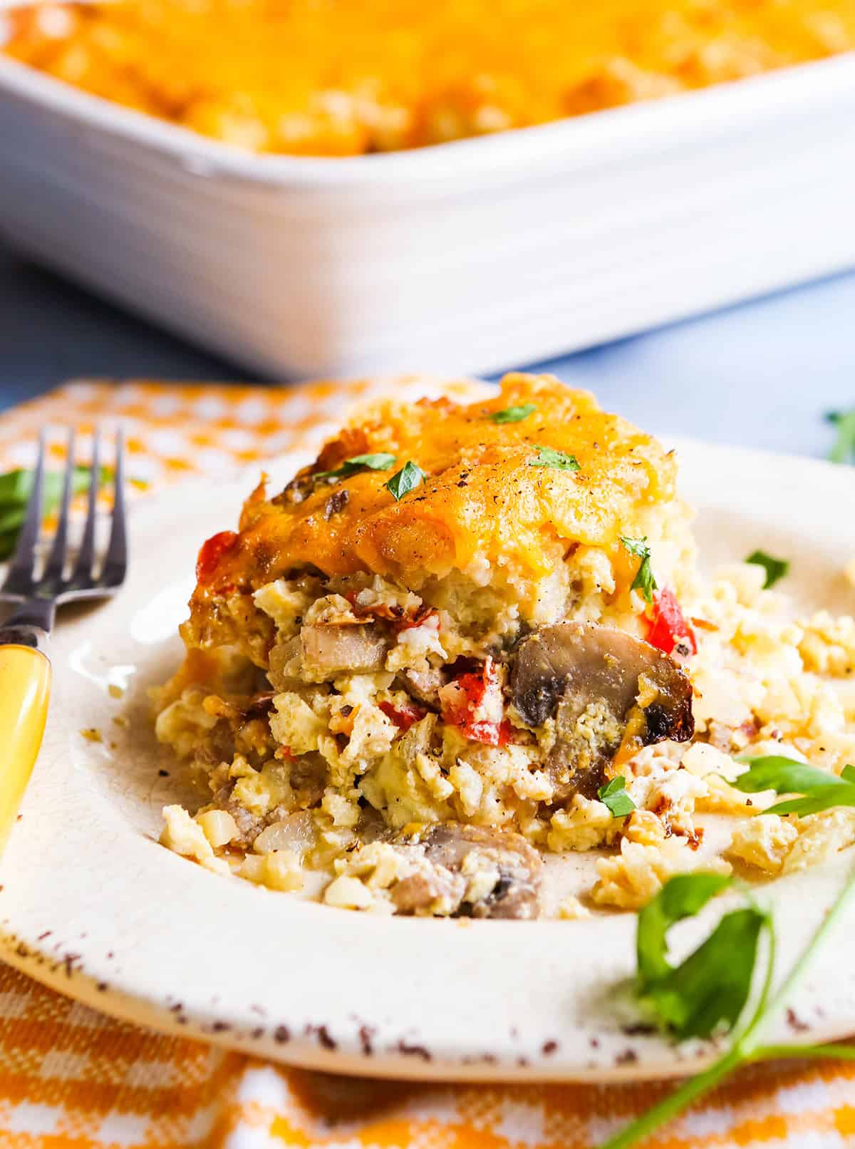 Piece of breakfast casserole on a plate, next to a baking dish.