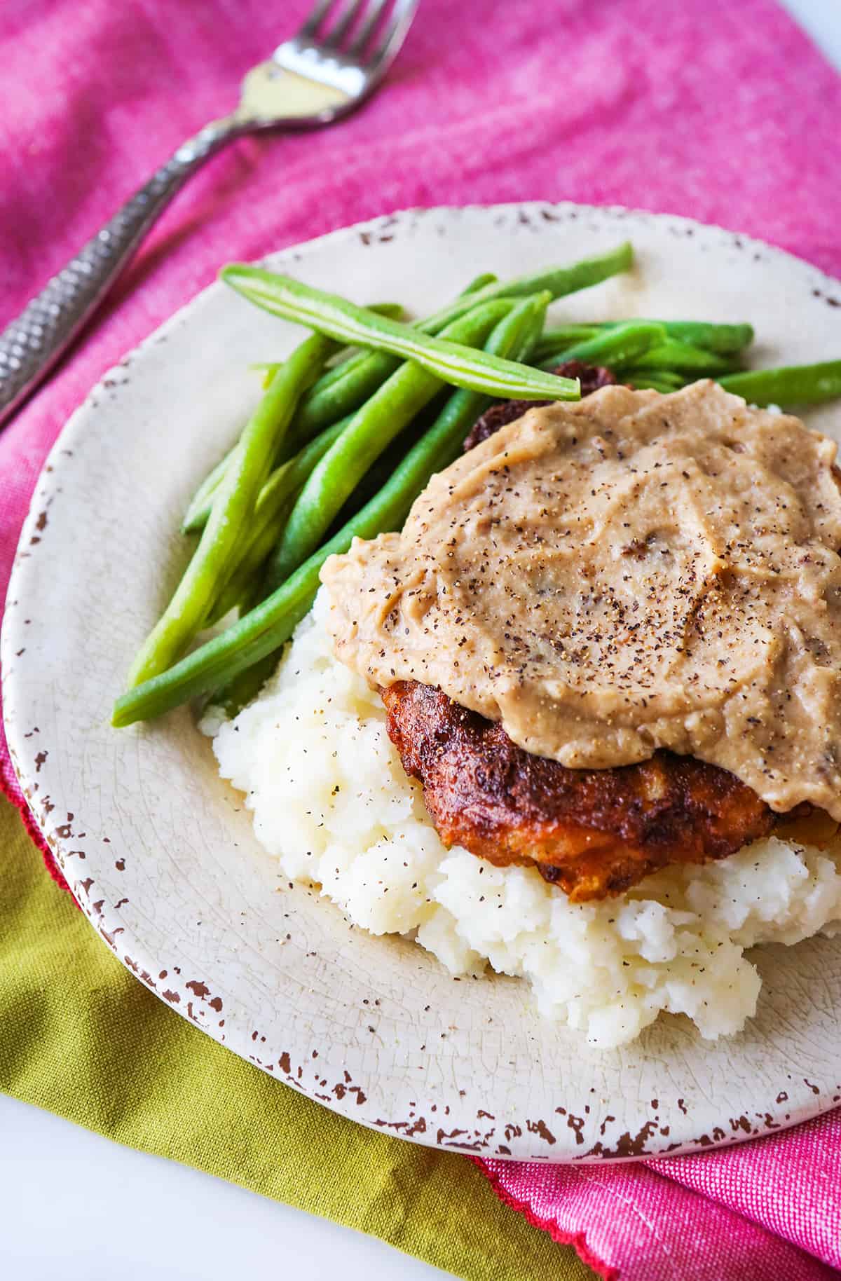 Plate of chicken fried steak on a pink placemat.