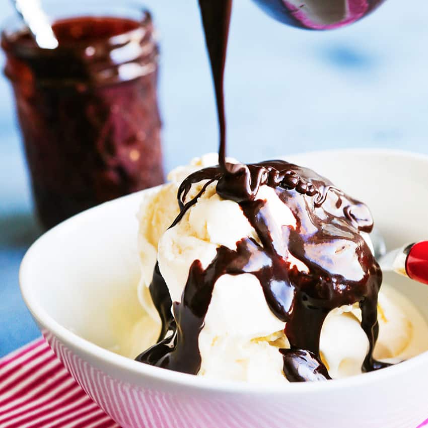 homemade hot fudge being drizzled over a bowl of vanilla ice cream