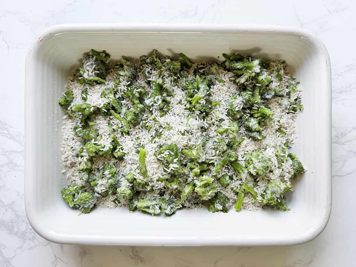 A layer of frozen broccoli in a baking dish, with a layer of white rice over the top.