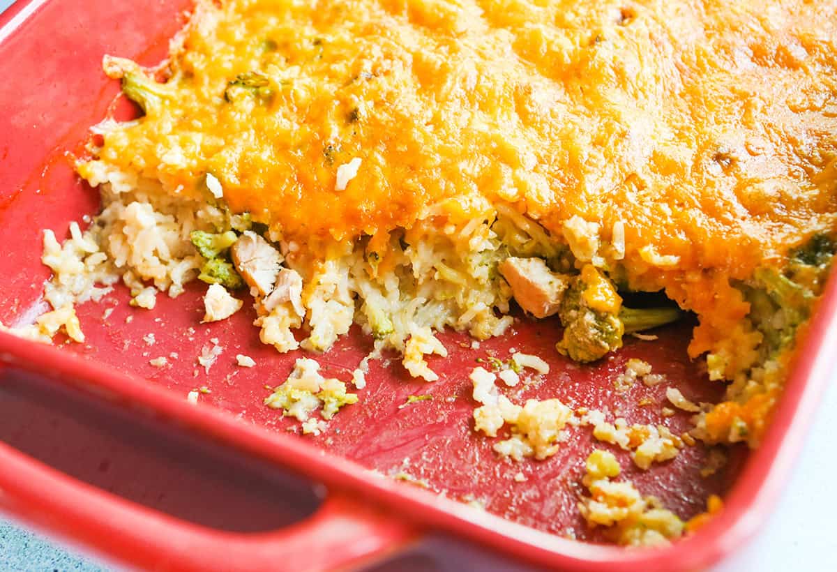 A few big spoonfuls have been removed from a cheesy broccoli rice casserole.