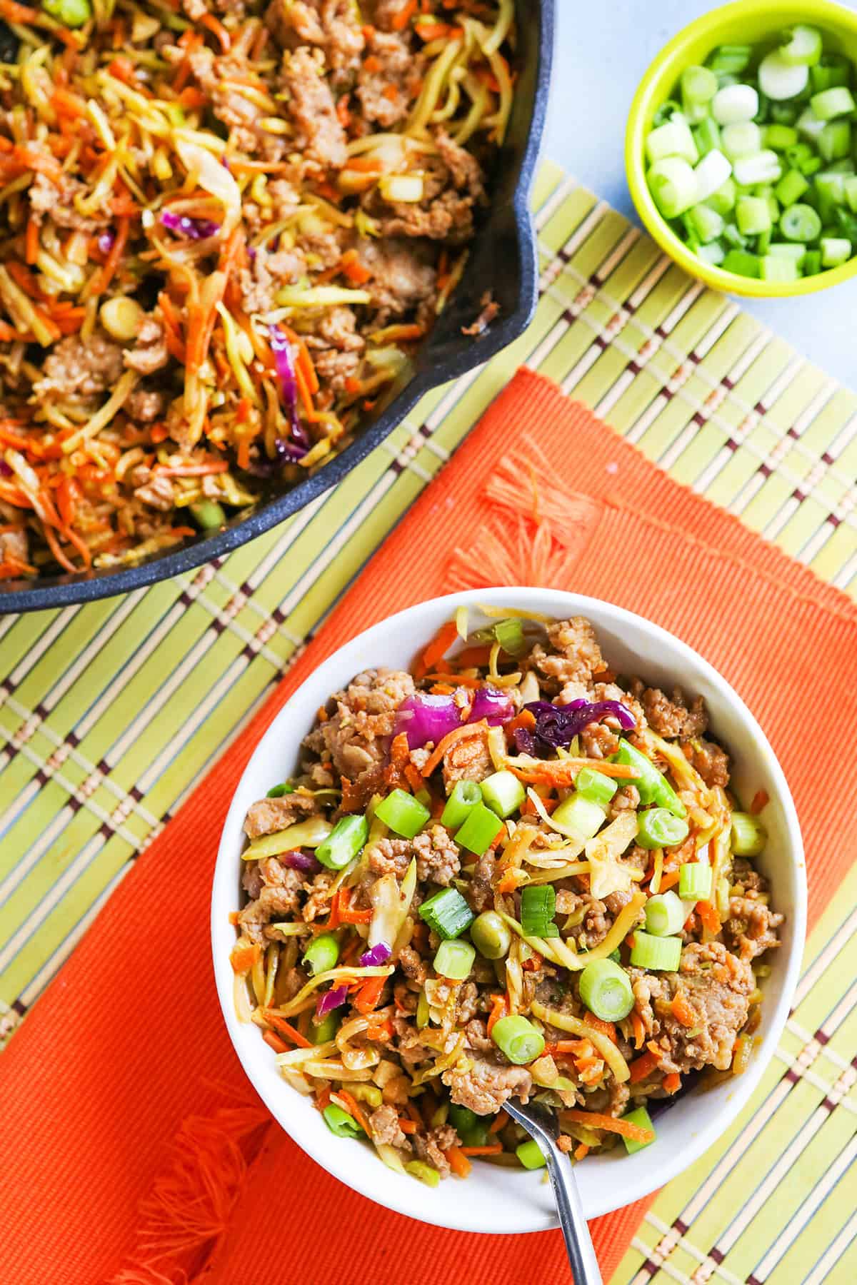 Egg roll in a bowl with vegetables and ground meat in a white dish.