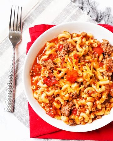 Delicious homemade goulash with pasta, beef, and vegetables in a white bowl.