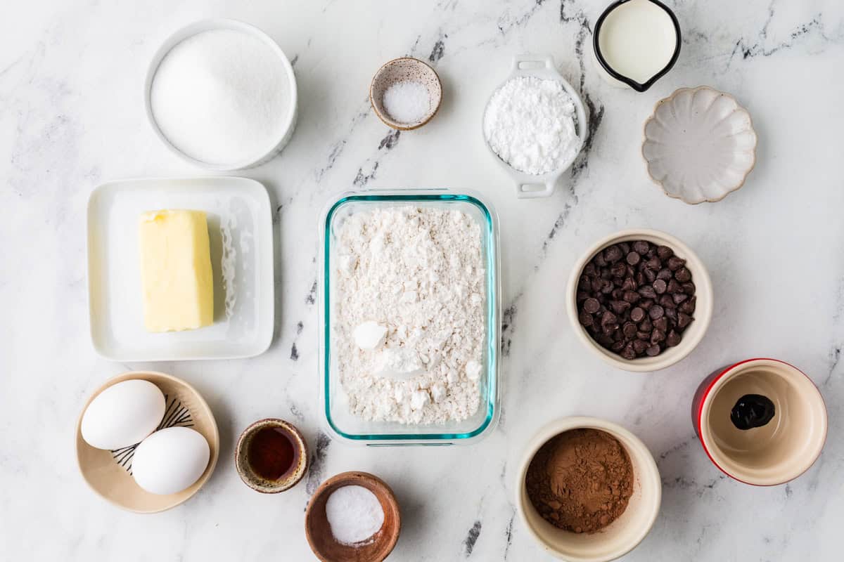 Brownie ingredients in individual bowls on a white counter.