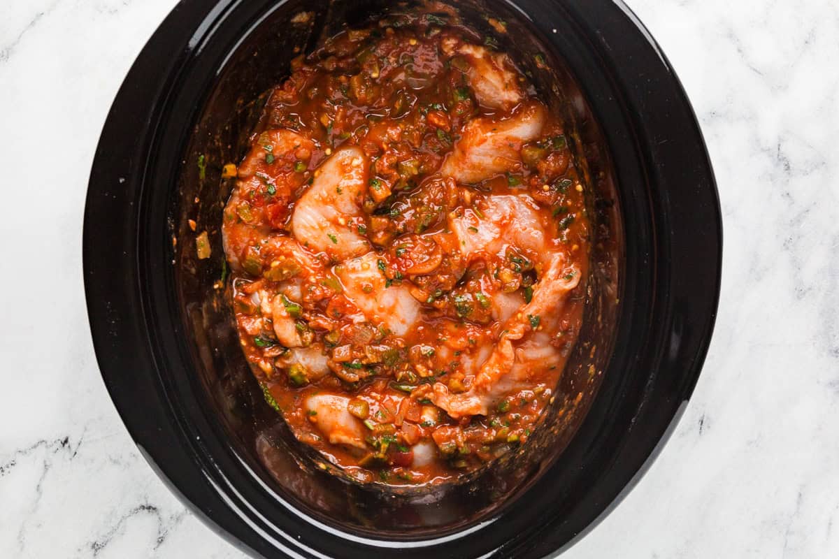 Chicken breasts and salsa mixture in a crockpot, ready to cook.