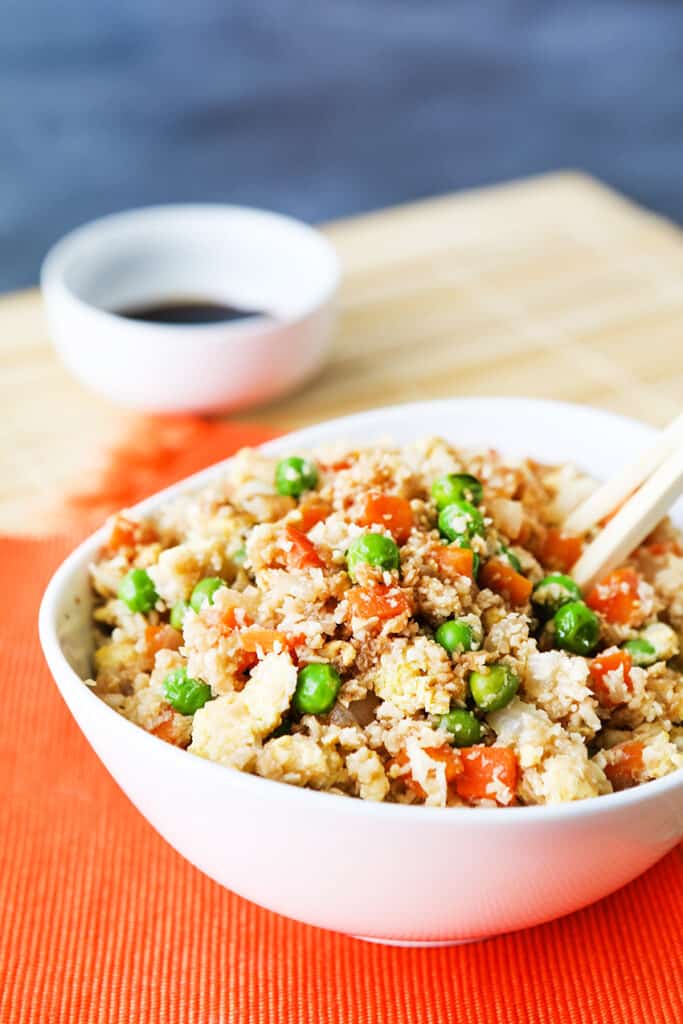 Choptsticks tucked into a bowl of cauliflower fried rice.