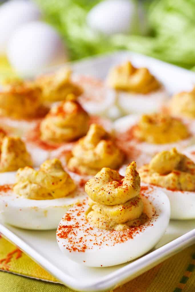 Serving plate of deviled eggs with paprika sprinkled on top.