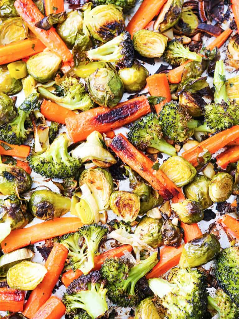 Roasted veggies (broccoli, carrots and brussels sprouts) on a baking sheet. 