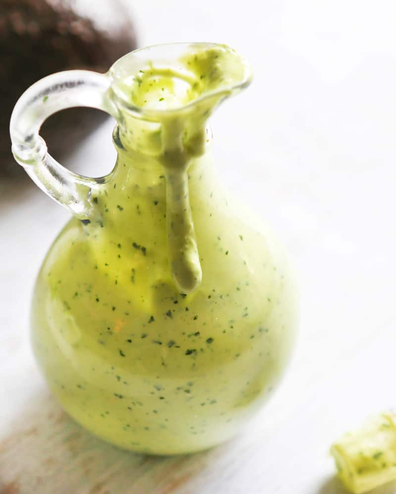 Green avocado dressing in a container ready to pour.