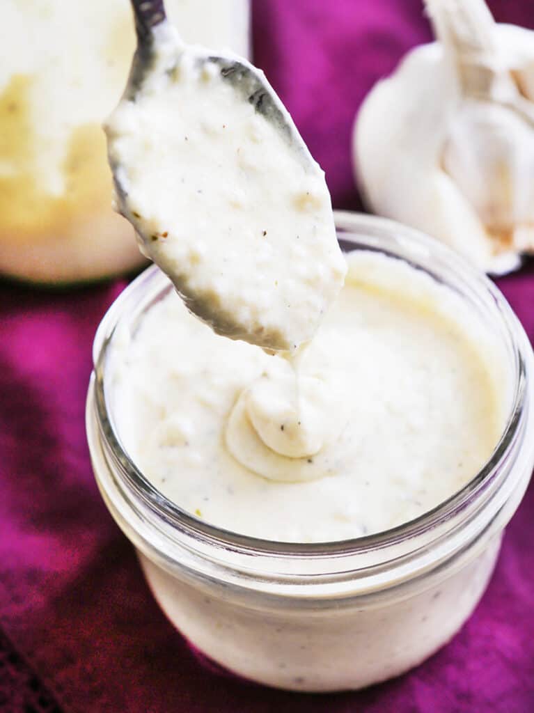 Spoon drizzling homemade alfredo sauce into a mason jar