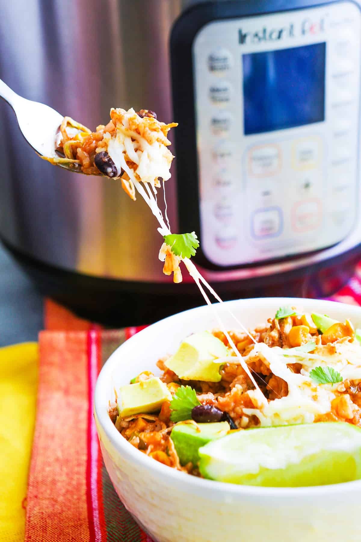 Fork taking a bite of instant pot chicken chipotle out of the bowl with a lime wedge on the side. 