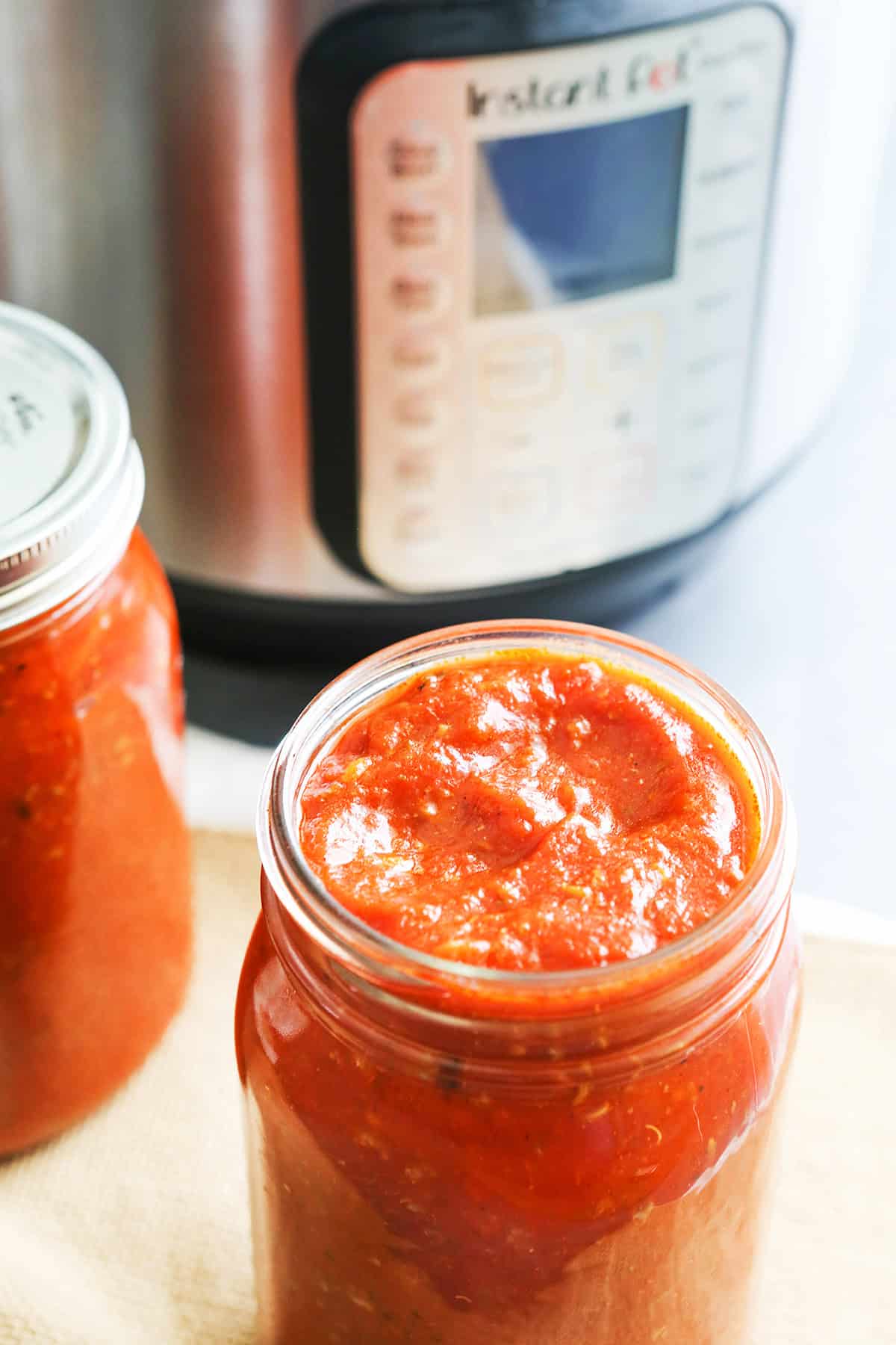 Two mason jars of spaghetti sauce sitting next to an instant pot.