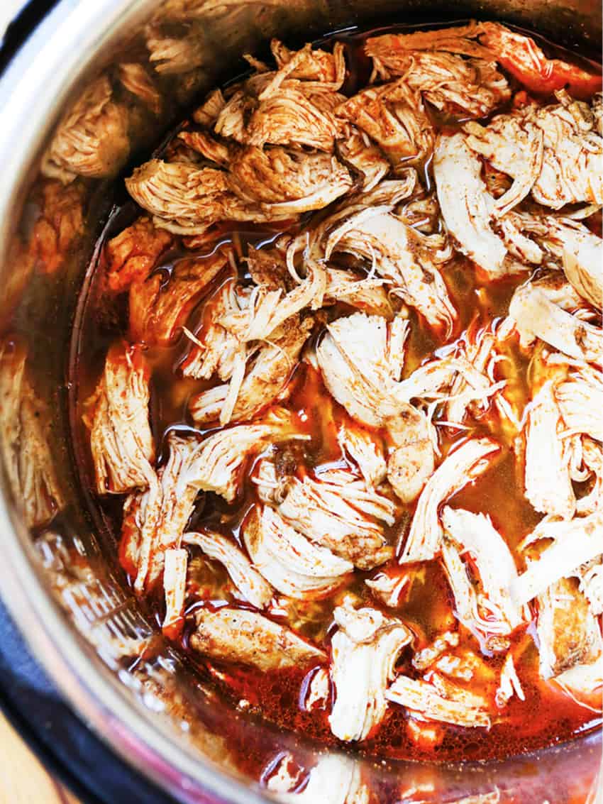 Shredded chicken tacos in seasoning inside an instant pot. 