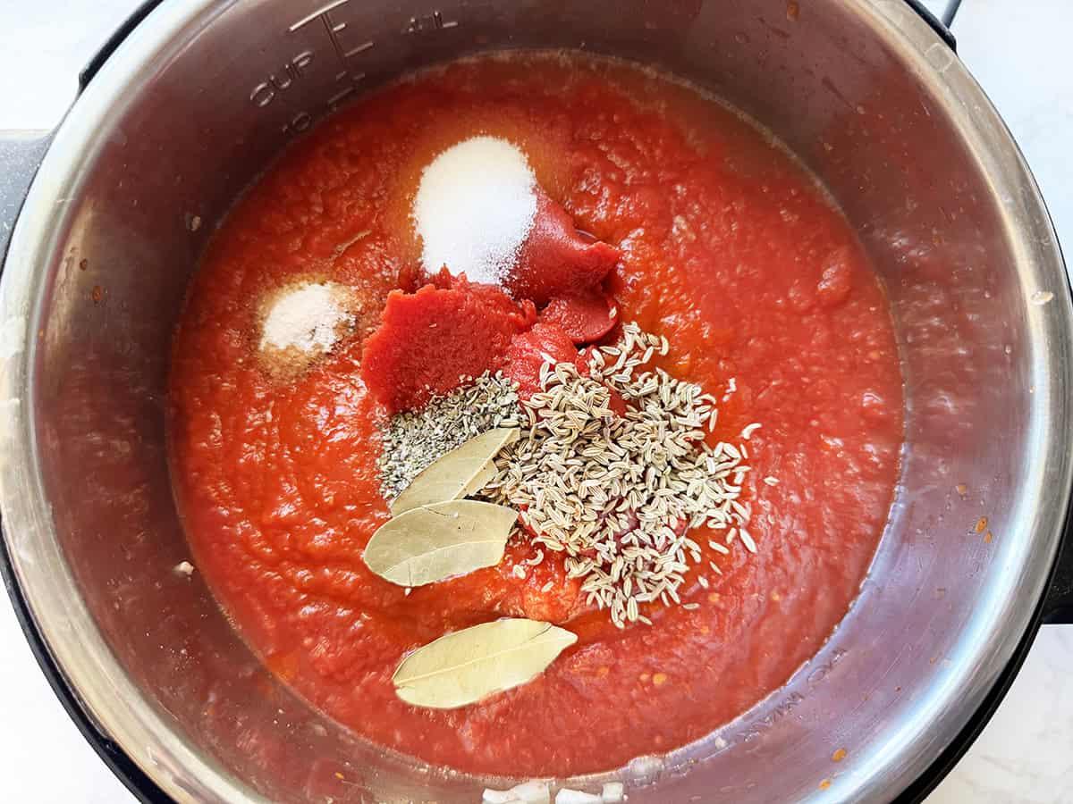 Pasta sauce in an Instant Pot with spice on top, ready to stir.