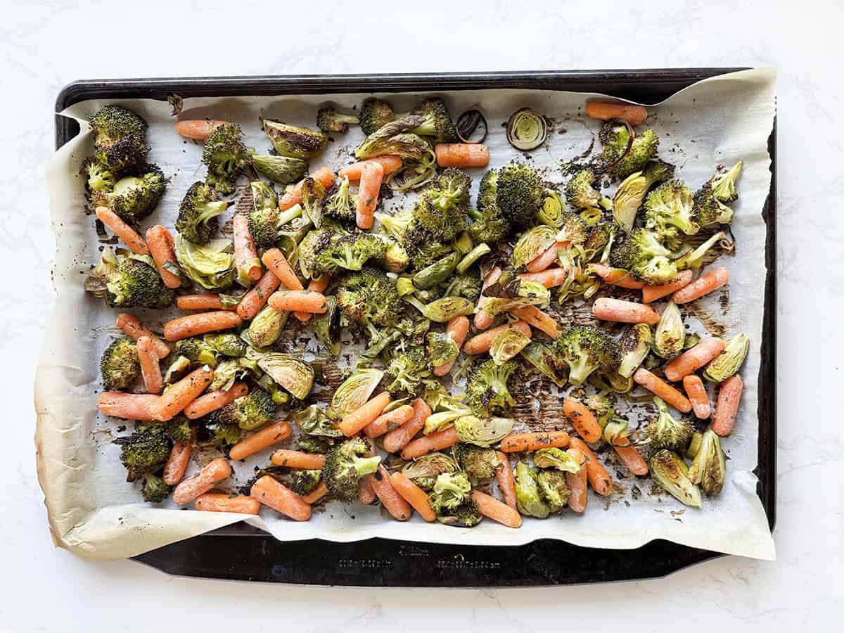 Roasted veggies on a parchment lined baking sheet.